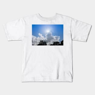 Sun bursts above cloud against blue sky. Kids T-Shirt